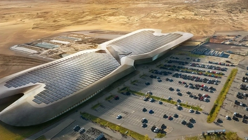 Aerial render of a wing-shaped solar-roofed building in a desert with a large car park and arid terrain